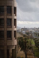 A modern high-rise stands along the Tel Aviv coast, with the skyline of Yafo (Jaffa) in the distance. The corporate office building expresses the bustling Israeli economy.