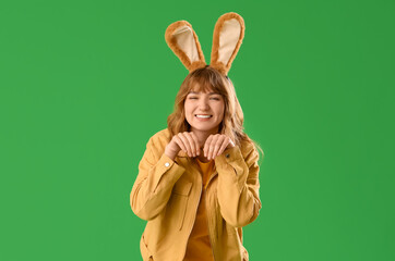 Young girl with Easter bunny ears on green background