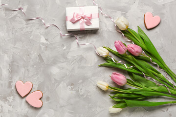 Tulip flowers with gift box and cookies in shape of hearts on grey grunge background. International Women's Day celebration