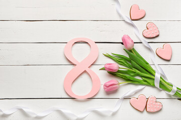 Figure 8 made of paper with tulip flowers, cookies and ribbon on white wooden background. International Women's Day celebration
