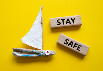 Stay Safe symbol. Concept word Stay Safe on wooden blocks. Beautiful yellow background with boat....