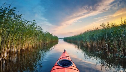 kayak among reeds on evening river - obrazy, fototapety, plakaty