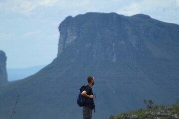 homem em trilha na Chapada Diamantina, Bahia, com motanhas ao fundo