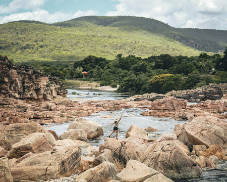 mulher caminhando em pedras no Rio Paraguaçu em Andaraí, na Chapada Diamantina, Bahia