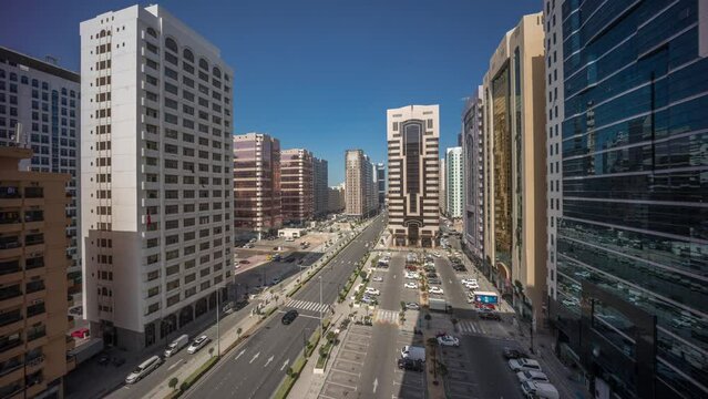 Residential buildings and modern city architecture of Abu Dhabi aerial timelapse during all night to sunrise, UAE. View from above to cars on parking lot and long shadows from towers with skyscrapers