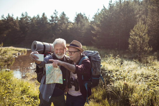Senior men in nature with smartphone and map - Powered by Adobe