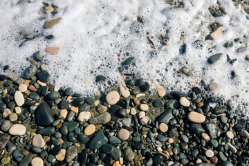 Stones and sea foam on the beach  