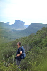 Fototapeta na wymiar homem de mochila nas costas em trilha na Chapada Diamantina, Bahia, com motanhas ao fundo