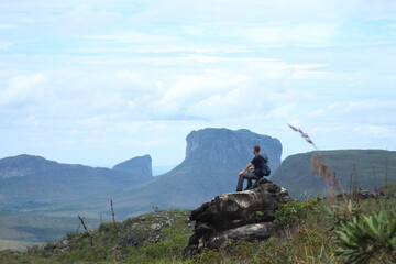 homem de mochila nas costas em trilha na Chapada Diamantina, Bahia, com motanhas ao fundo