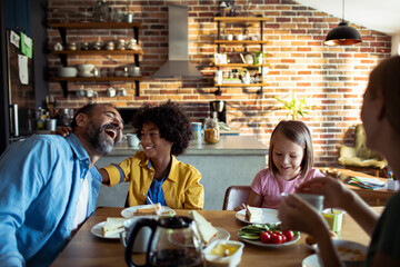 Young mixed family eating together at home - obrazy, fototapety, plakaty