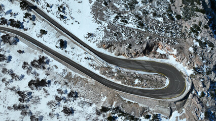 Aerial drone photo of dangerous snowed curvy mountain road as seen at winter