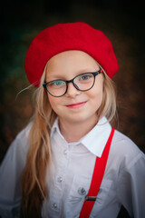 Little blonde girl in a red beret and glasses close-up
