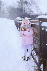 Portrait of a beautiful little girl with a bear in her hands in winter