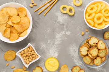 Various unhealthy snacks on concrete background, top view