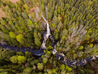 Plodda Falls, waterfall surrounded by pine trees, highland, Scotland drone shot
