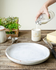 the table set for breakfast, a hand pouring milk into a glass, the atmosphere of the village