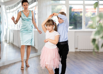 Small passionate ballroom enthusiasts, tween girl and boy practicing graceful waltz routine in...
