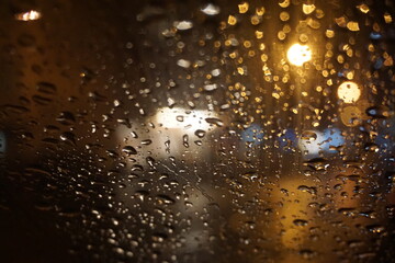 Abstraktes Motiv mit Regentropfenmuster vor goldweißem Licht und Autos auf nasser Straße mit...