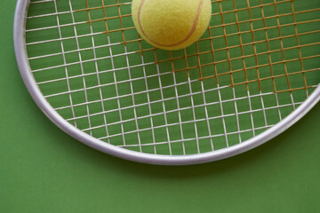 A tennis ball for big tennis lies on a racket on a green background