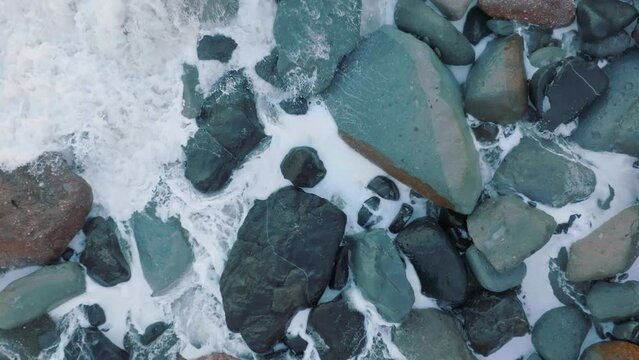 Aerial: Waves crashing over boulders in slow motion. Oamaru, Otago, New Zealand.