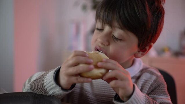 Young Boy Seated at Table Enjoying a Bite of Bread, Simple Meal, 5 year old child eating carb food