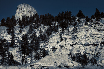 Devil's Tower looms above an eroded cliff — monochrome (two color) treatment to simulate a...