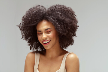 Overjoyed afro woman laughs out loudly. Real people emotions