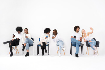 Happy diverse group of multi ethnic friends smiling while using mobile phones, having fun together