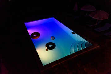 A night shot of a private residential swimming pool with underwater lighting