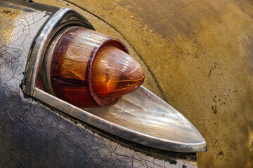 Old vintage car taillight in need of restoration in lively colors.