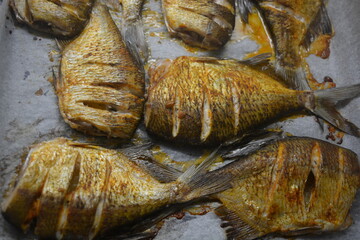 Delicious and healthy, baked fish, Carassius with lemon on a black baking sheet with white parchment paper.