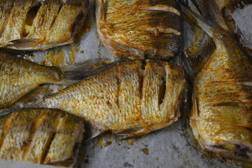 Delicious and healthy, baked fish, Carassius with lemon on a black baking sheet with white parchment paper.