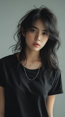 Attractive young Asian woman in simple black t-shirt with silver necklace and messy hair