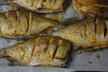 Delicious and healthy, baked fish, Carassius with lemon on a black baking sheet with white...