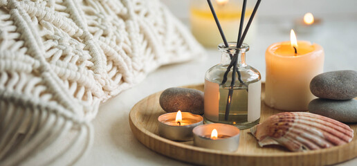 Apartment natural aroma diffusor with sea breeze fragrance. Burning candles on bamboo tray, cozy home atmosphere. Relaxation, detention zone in the living or bedroom. Stones as decor. Banner - obrazy, fototapety, plakaty