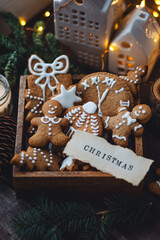 Traditional holiday homemade gingerbread cookies in a vintage wooden box. Craft paper with Christmas word on it. Festive mood, cozy home atmosphere, handmade toys, fir tree branches, fairy lights