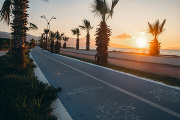 Sunset over the beach with a bike line in the foreground. Blue bike line next to the beach.