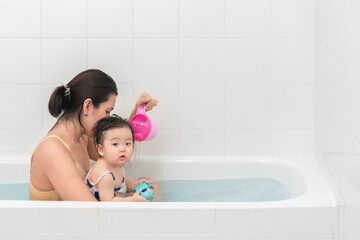 Asian mother and baby girl bathing together in bathtub, Happy lifestyle family concept.