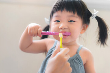 Asian mother and daughter brushing their teeth together, Mom teaching his daughter how to brush teeth, Oral health concept