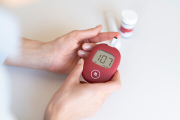 A young woman measures her blood sugar level using a glucometer.