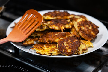 potato pancakes on a plate on a black plate with a kitchen spatula on top