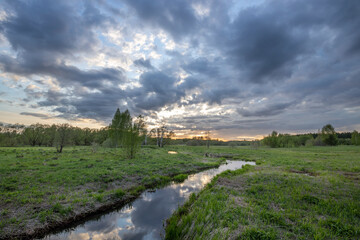 Fototapeta na wymiar Dramatic sky over the river, spring landscape and green grass along the river