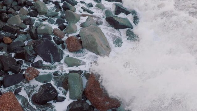 Aerial: Waves crashing over boulders in slow motion. Oamaru, Otago, New Zealand.