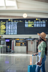 vertical portrait latin traveler girl looking at time tables in terminal