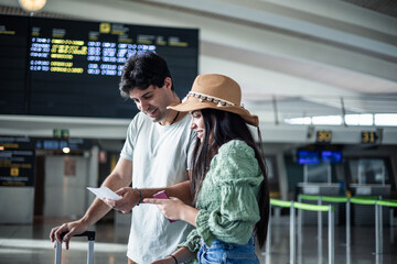 multicultural couple at the airport checking their boarding pass