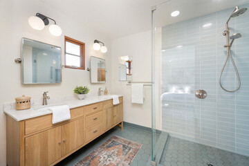 a white bathroom with tiled walls and wood cabinets and a sky blue tiled floor