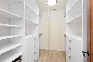 an open closet with white drawers and shelves on each side