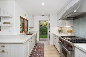 a kitchen with white cabinets, stainless appliances and wooden floors