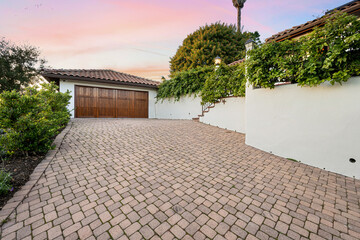 a driveway with brick pavers, and a garage in the background