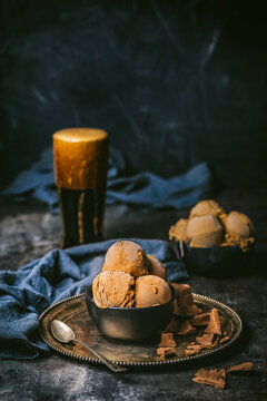 Front shot of black bowl with 3 scoops of chocolate ice cream and a frothy pint of dark stout beer with dark blue linen cloths